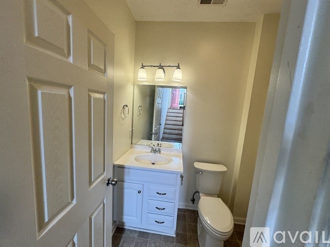 A bathroom with a toilet, sink, and mirror.