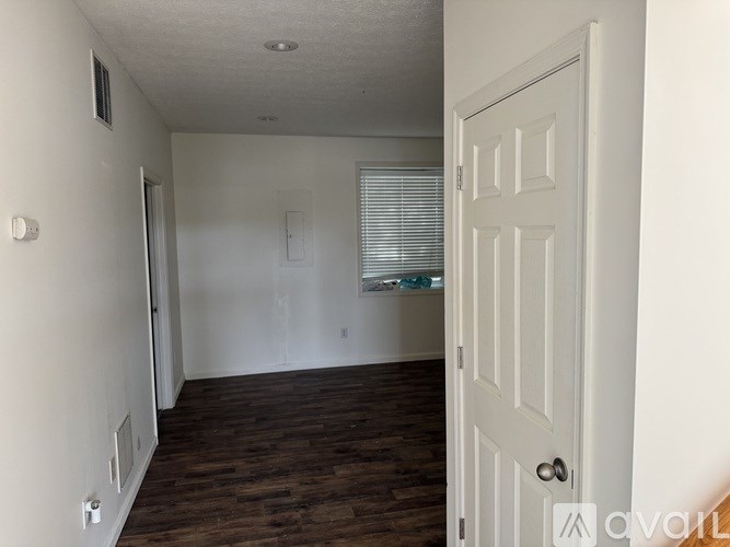 A room with a white door and wooden flooring.