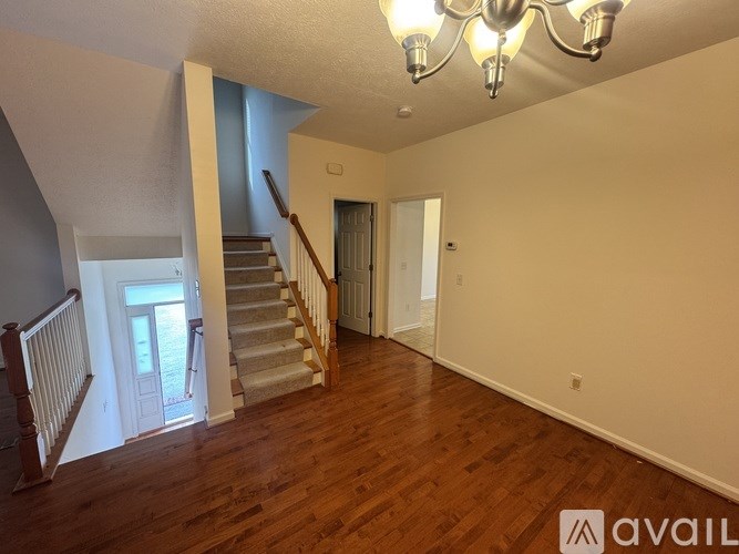 A spacious room with wooden floors and a chandelier.
