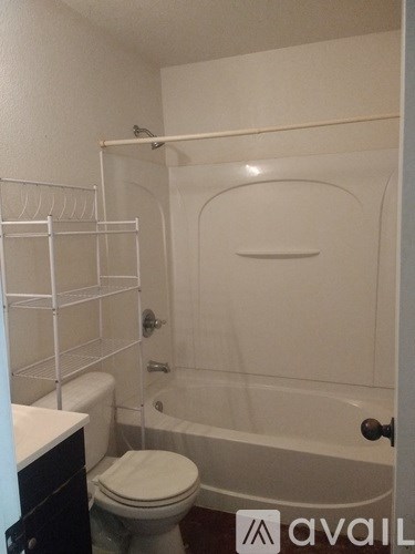 A bathroom with a toilet, a bathtub, and a towel rack.