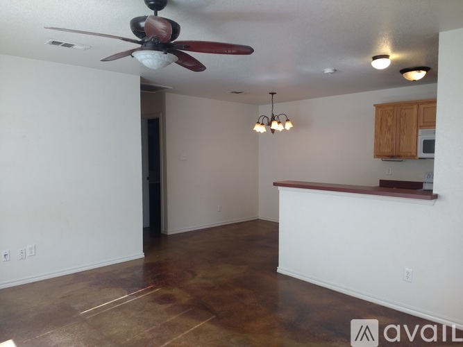 A room with a ceiling fan and a bar area.