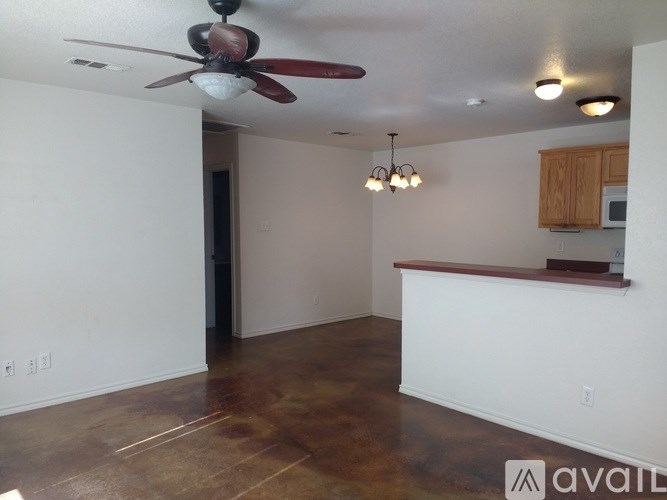 A room with a ceiling fan and a bar area.