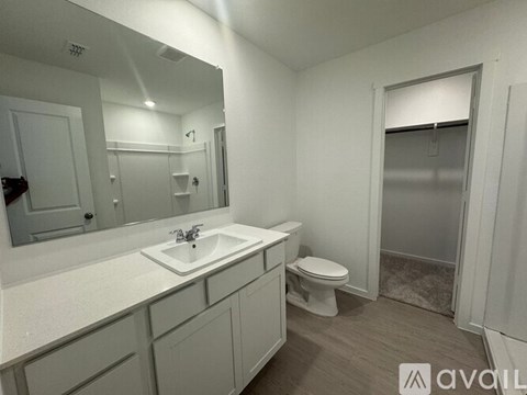 A bathroom with a sink, toilet, and mirror.