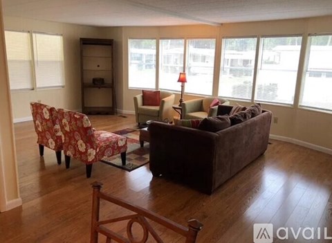 A living room with a brown couch, a chair with a floral pattern, and a wooden floor.