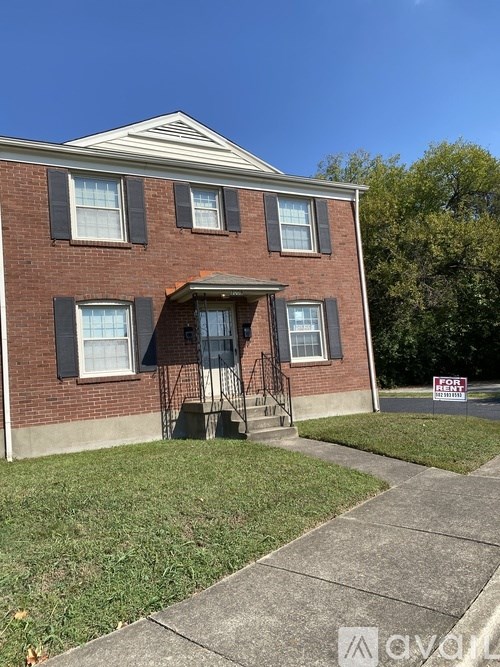 A red brick house with a sign that says "For Sale".
