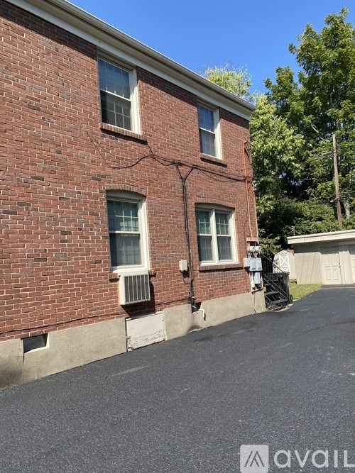 A red brick building with a white window and a tree in front.