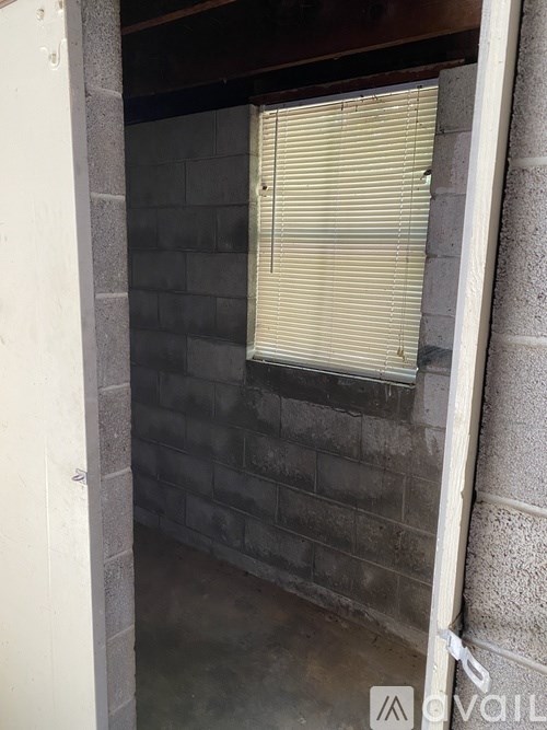 A window with blinds is on a brick wall.