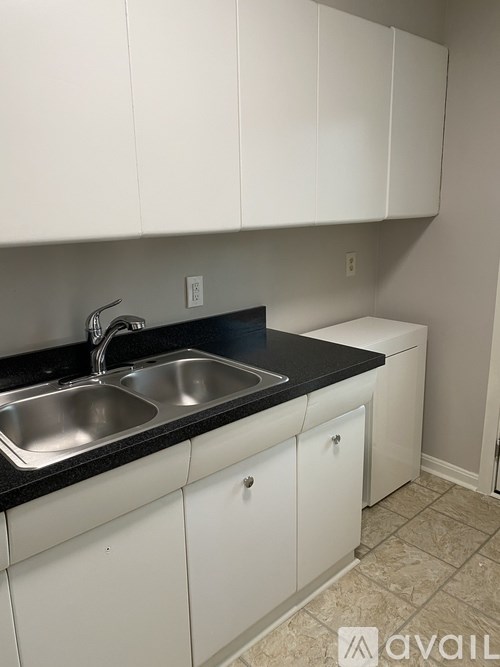 A kitchen with white cabinets and a black countertop.