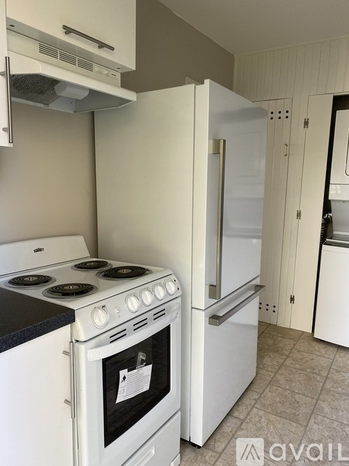 A white kitchen with a stove and refrigerator.