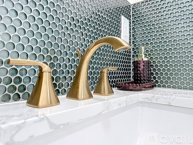A bathroom sink with a gold faucet and a soap dispenser.