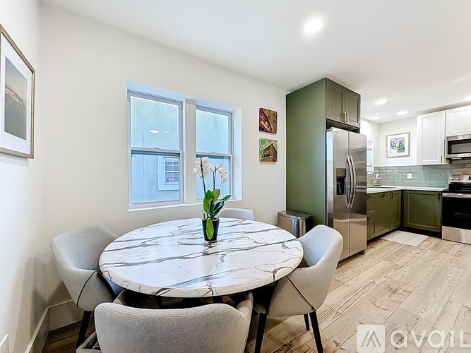A kitchen with a table and chairs in the foreground and a refrigerator in the background.