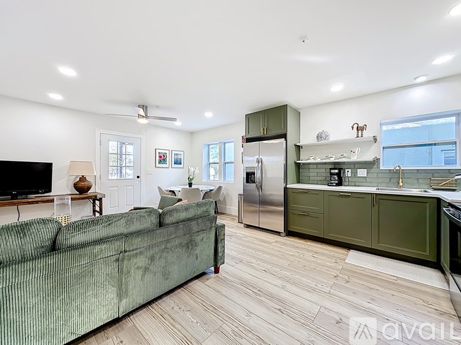 A living room with a green couch and a kitchen in the background.