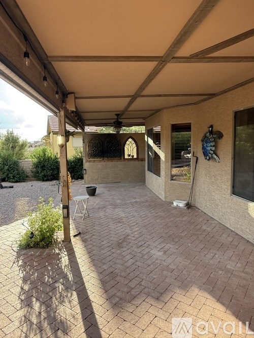 A patio area with a table and chairs under a roof.