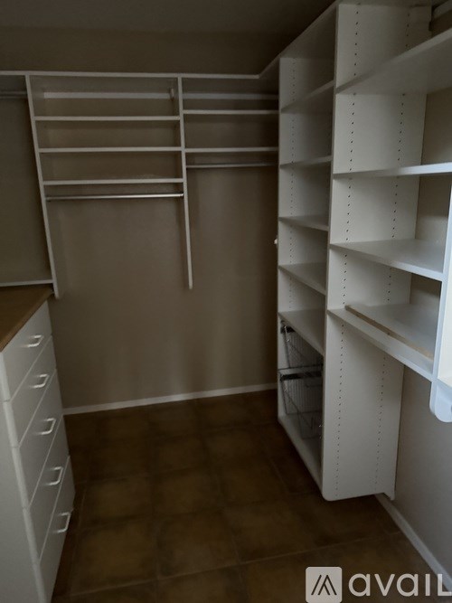 A white shelving unit in a room with brown flooring.