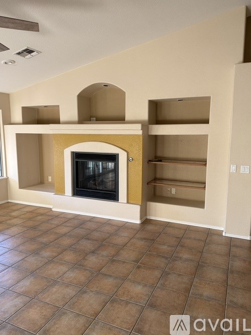 A living room with a fireplace and shelves.
