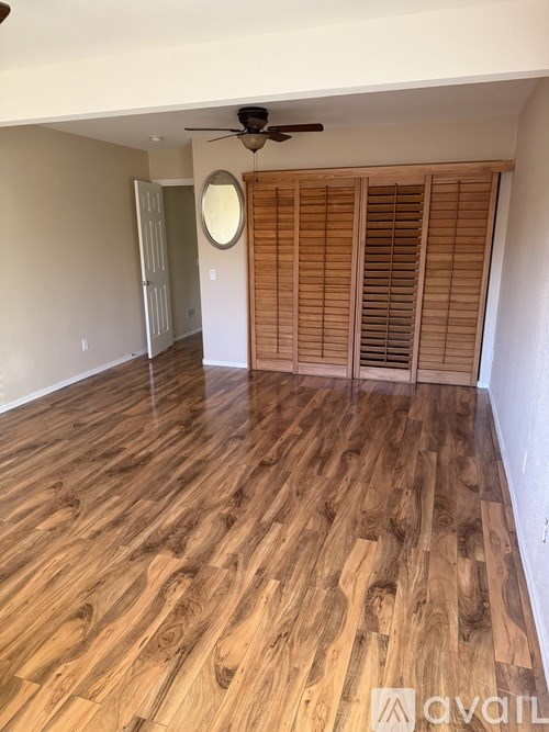 A room with wooden flooring and a ceiling fan.