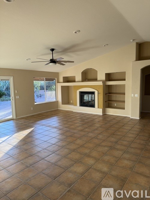 A spacious living room with a fireplace and a ceiling fan.