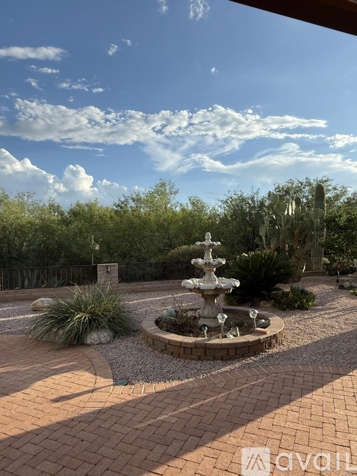 A garden with a fountain in the middle of a brick path.