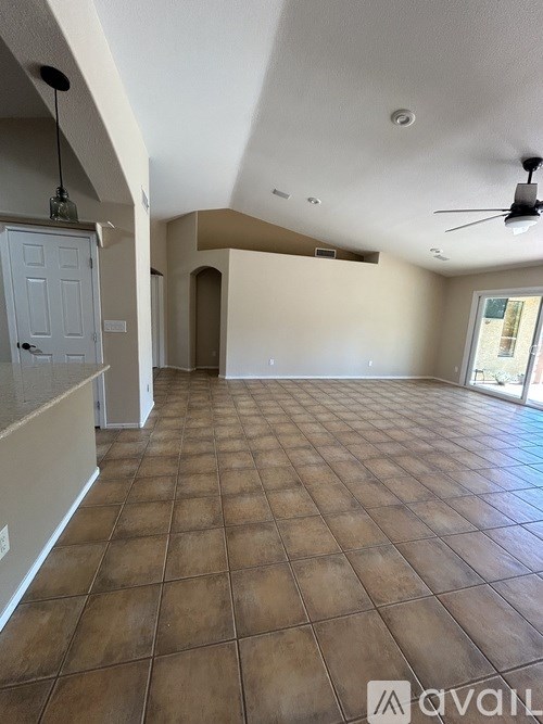A spacious room with tiled flooring and a ceiling fan.