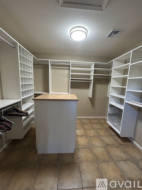 A walk-in closet with a wooden counter and white shelving.