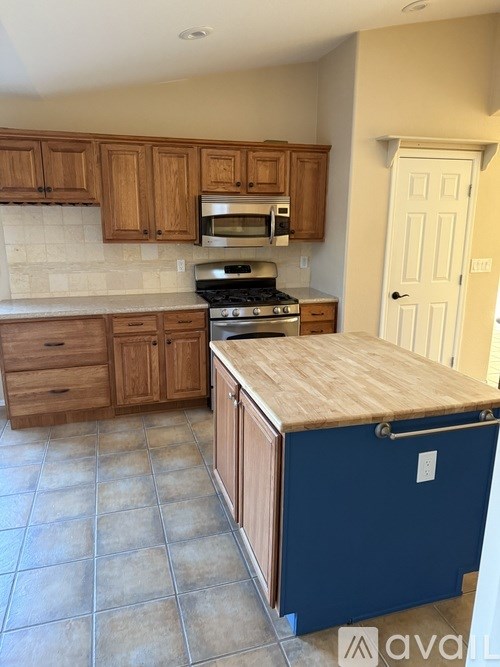 A kitchen with wooden cabinets and a blue island.