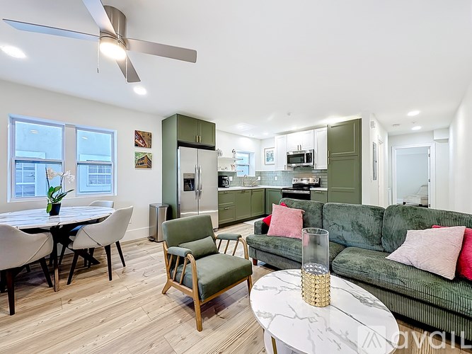 A living room with a green couch and a dining table with chairs.