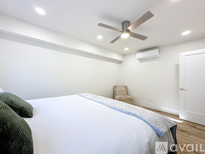 A bedroom with a bed, chair, and ceiling fan.