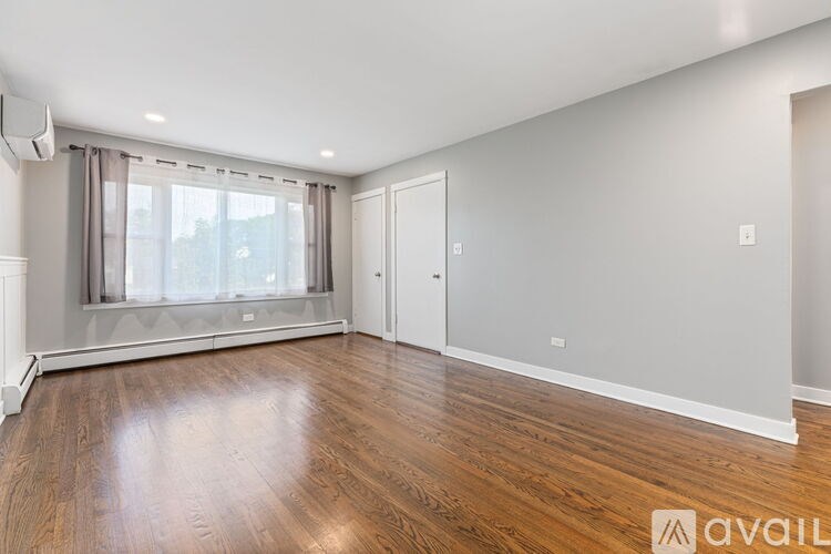 A room with wooden floors and a window with curtains.