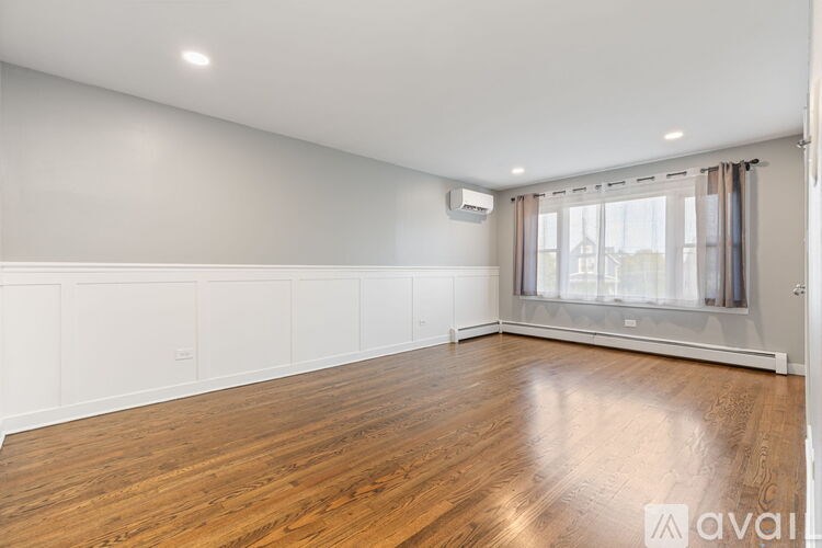 A spacious room with wooden flooring and white walls.