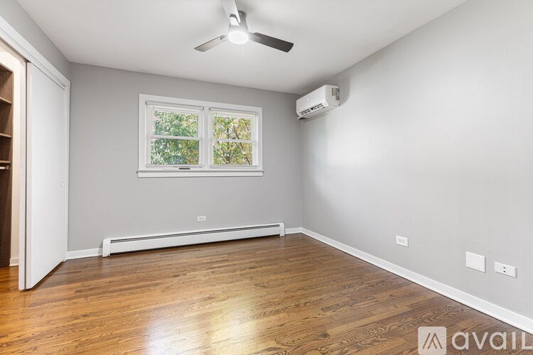 A room with a window, a ceiling fan, and a wall-mounted air conditioner unit.