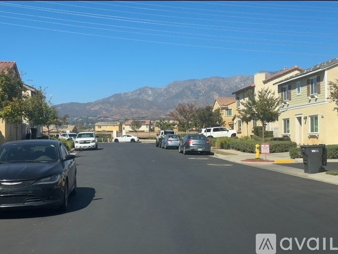 A black car is parked on the side of a street with other cars and houses on both sides.