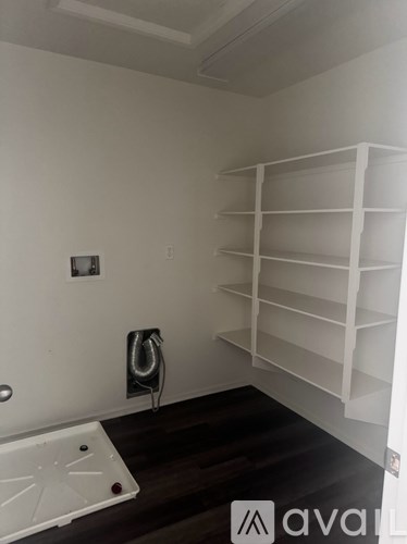 A white shelving unit in a room with a white wall and a black floor.