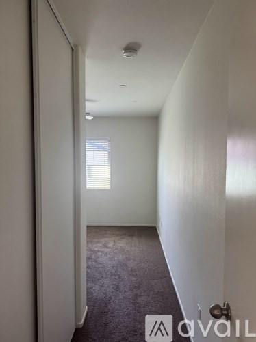 A hallway with a carpeted floor and white walls.