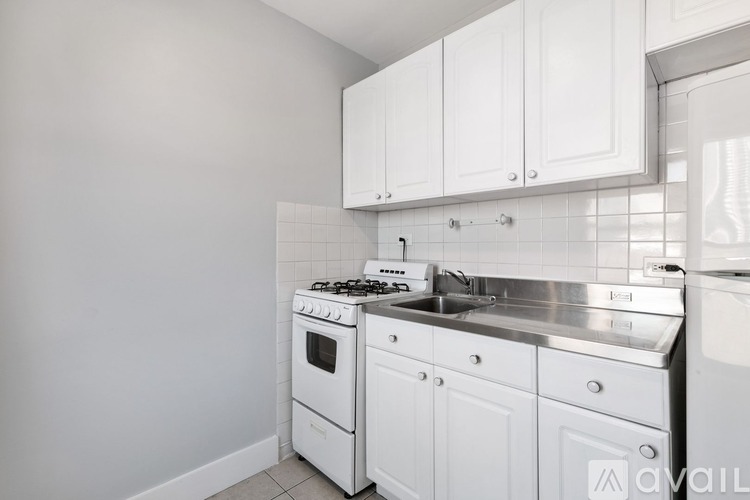 A white kitchen with a stove, sink, and cabinets.