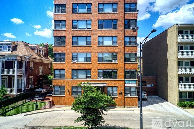 A tall red brick building with a balcony on the top floor.