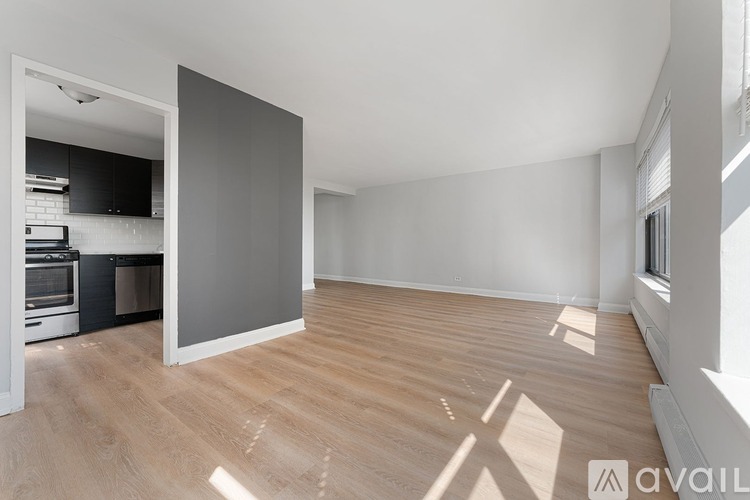 A spacious room with wooden flooring and a large grey wall.