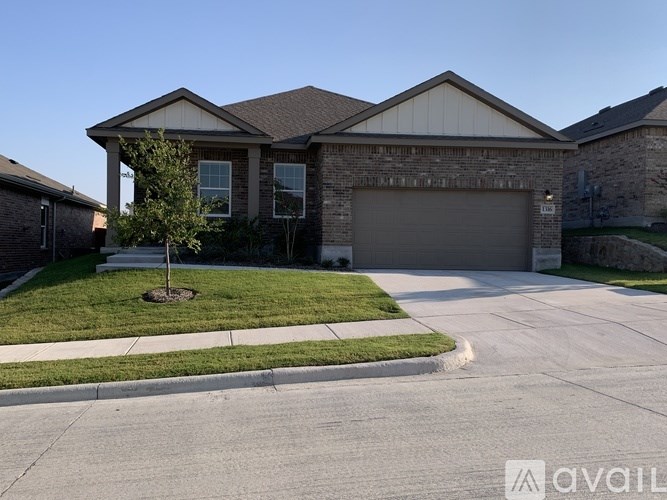 A house with a garage and a tree in front of it.