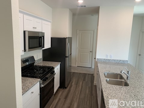 A kitchen with a black refrigerator and stove top oven.