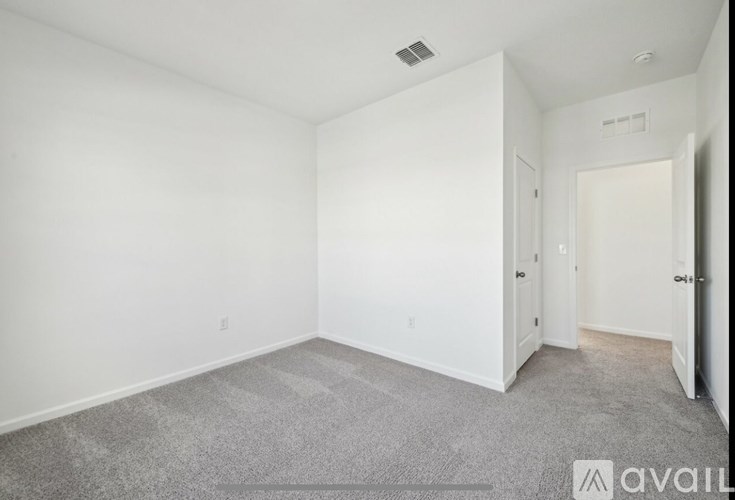 A spacious room with a carpeted floor and white walls.