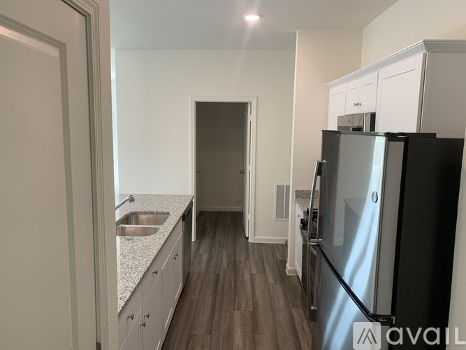 A kitchen with a black fridge and white cabinets.