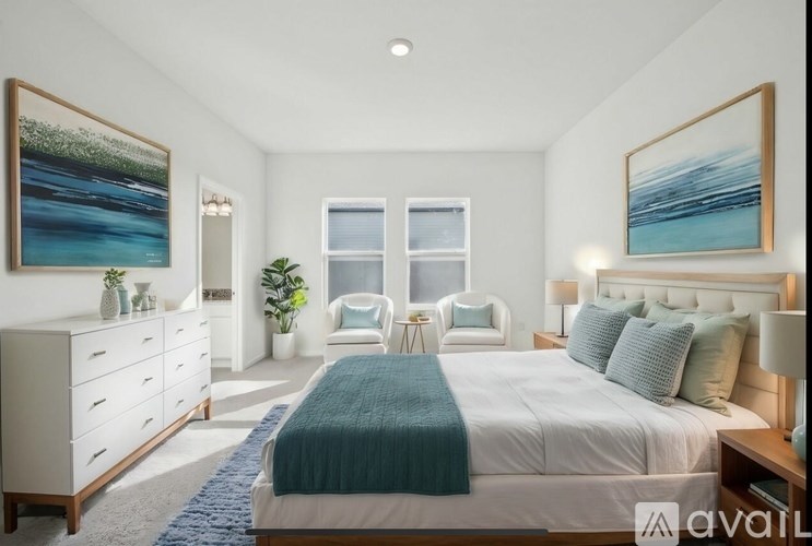 A bedroom with a large bed, a dresser, and two chairs.