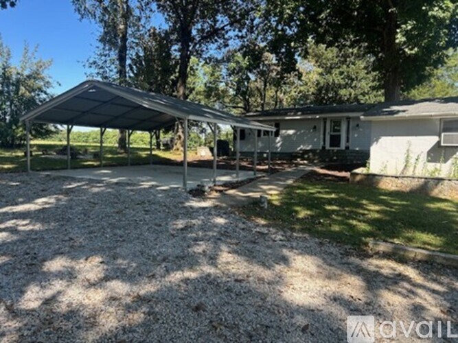 A gravel yard with a house and a carport.