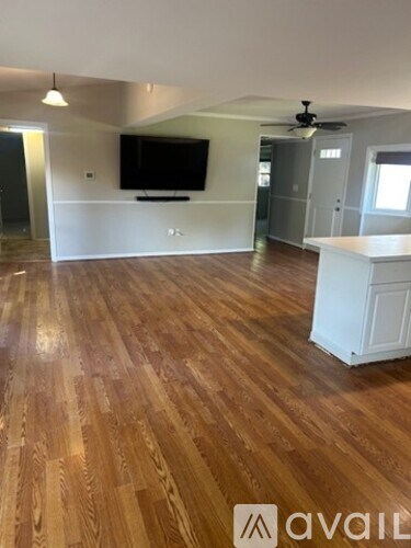 A room with wooden flooring and a television mounted on the wall.
