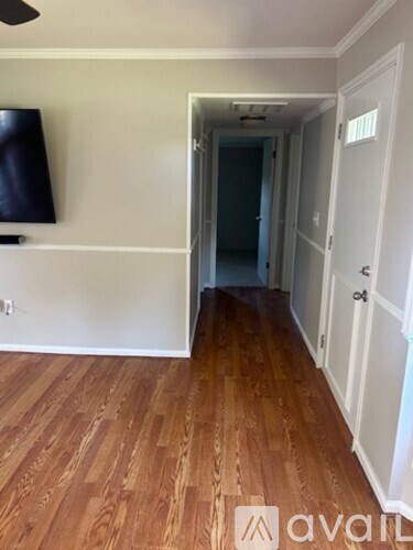 A hallway with wood flooring and white walls.