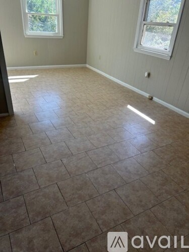 A room with tile flooring and two windows.