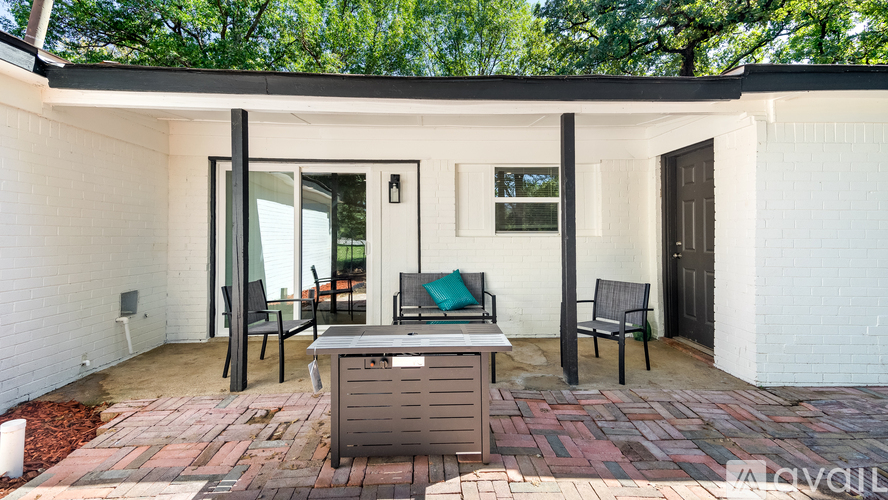 A white house with a brick patio and a black table and chairs.