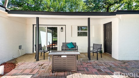 A white house with a brick patio and a black table and chairs.
