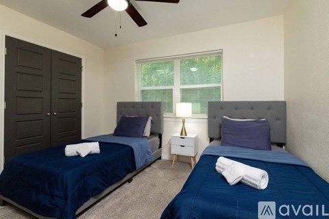 A bedroom with two beds and a ceiling fan.