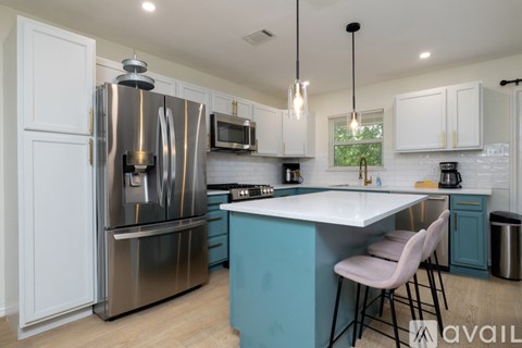 A kitchen with a blue island and white cabinets.