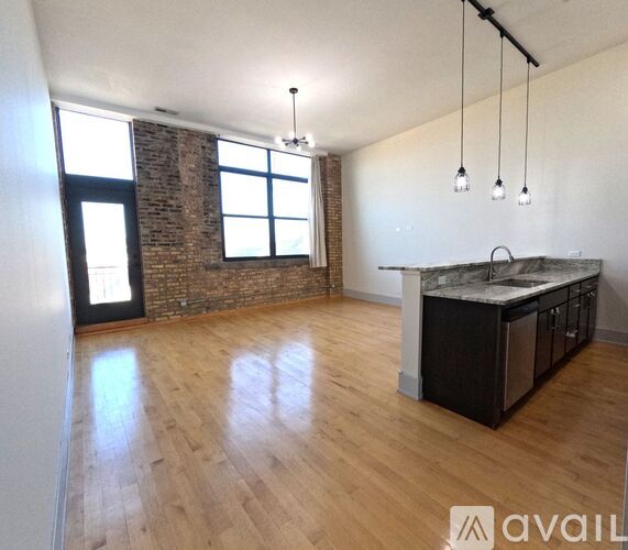 A kitchen area with a brick wall and wooden flooring.